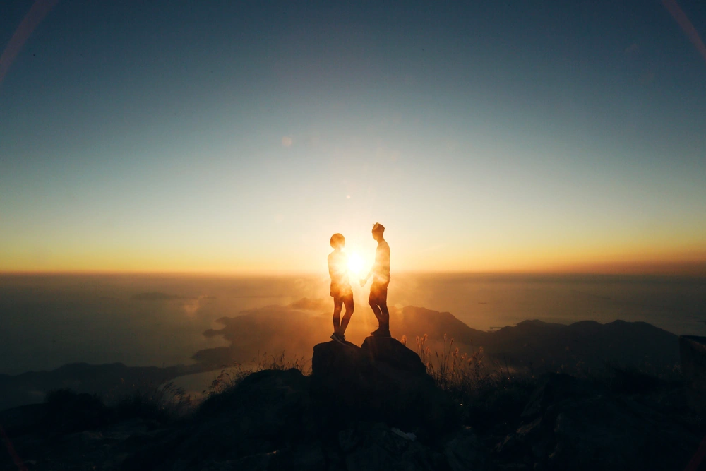 silhouette couple standing rock formation against sky sunset